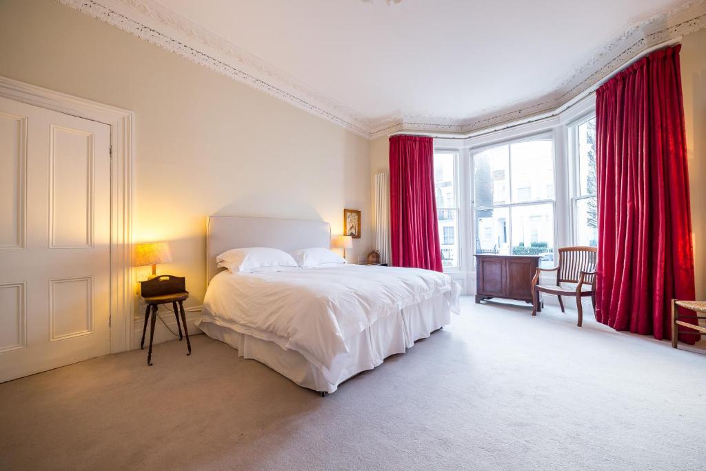 伦敦The Bockery Suite 1 Chelsea的一间卧室配有一张带红色窗帘的大床