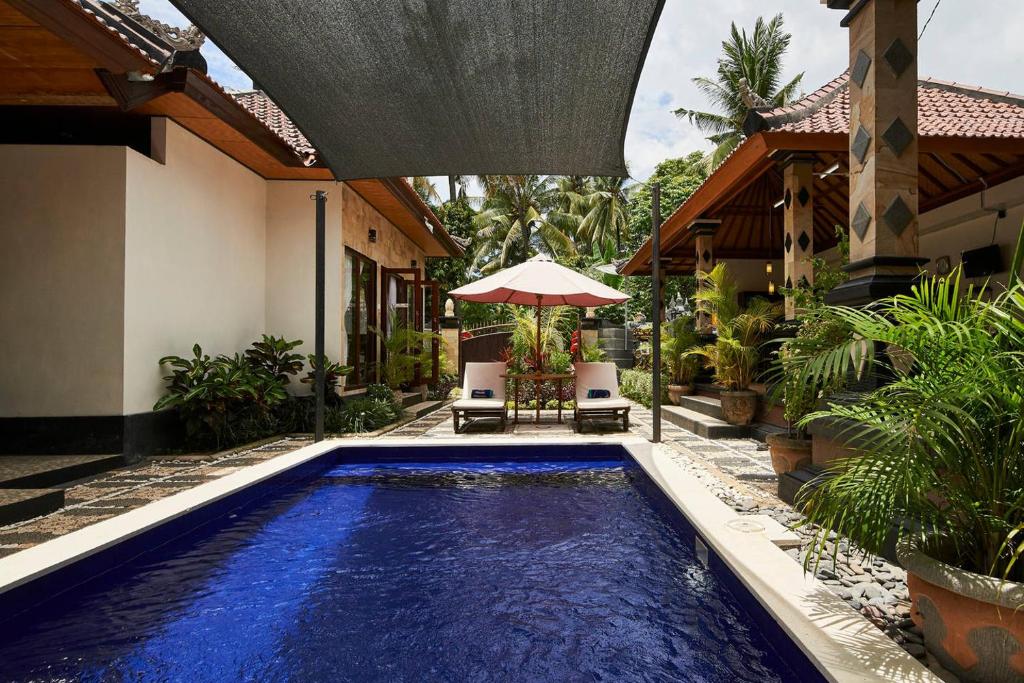 特贾库拉杰克逊别墅 的房屋前的游泳池配有两把椅子和一把遮阳伞