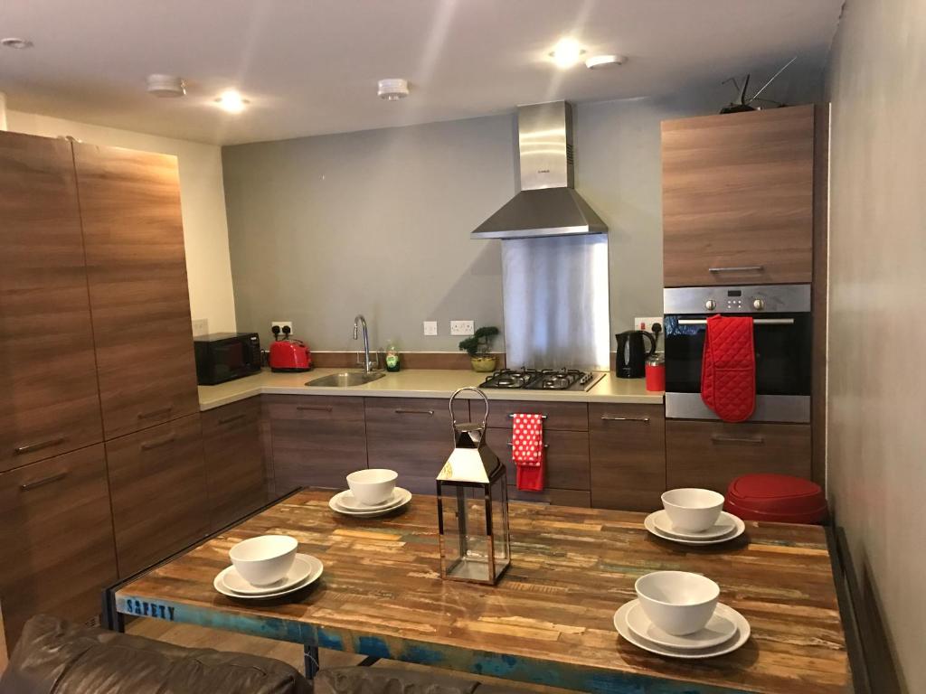 布伦特伍德Executive Brentwood Apartment的厨房配有带杯子和碟子的木桌