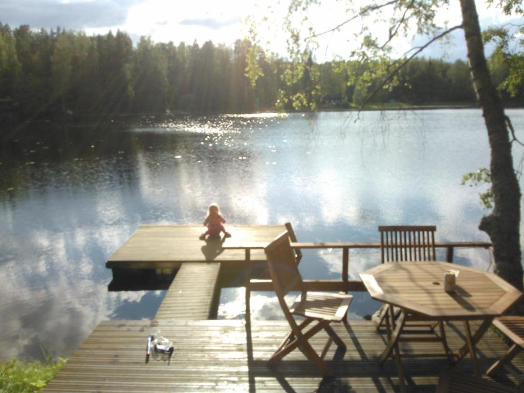KarjalohjaLohja Chalet at Lake Enäjärvi的坐在湖面上码头上的孩子