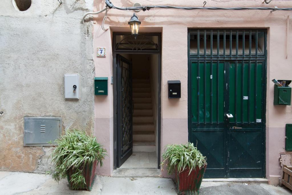 蒙德罗Holiday & House - Imparato Vacanze Prestige Mondello的两棵盆栽植物的建筑上的绿门