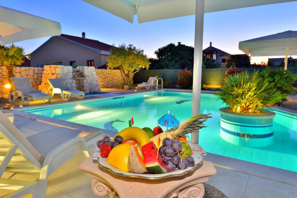 扎达尔Villa Dalmatina Zadar mit Pool的游泳池畔的桌子上放上一碗水果