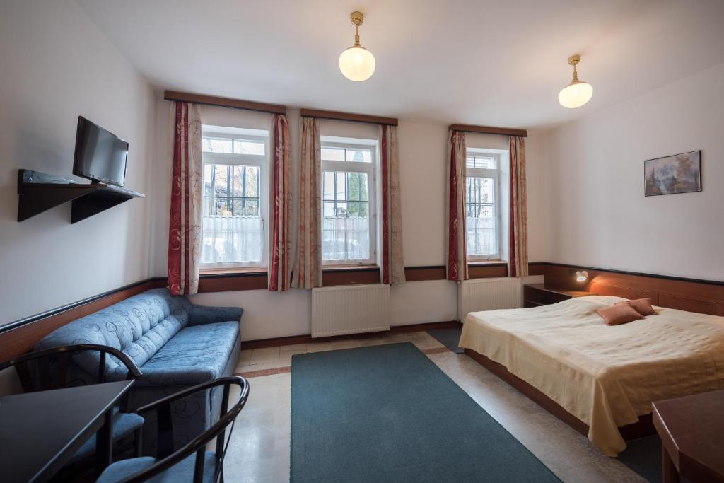 凯斯特海伊Abbázia Club Hotel Kék的一间卧室配有一张床、一张沙发和窗户。