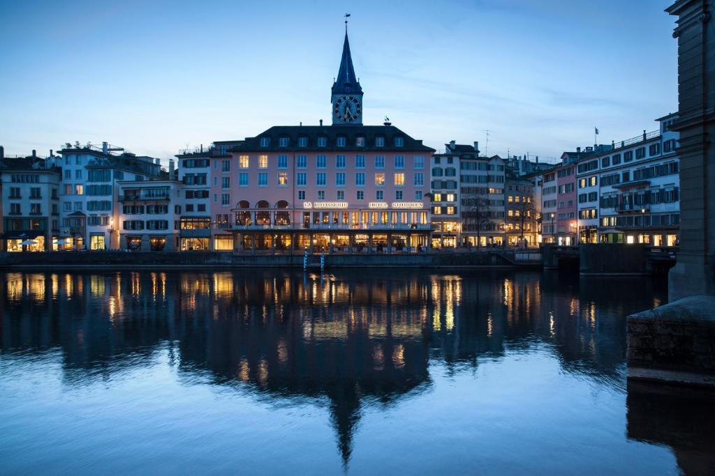 苏黎世Storchen Zürich - Lifestyle boutique Hotel的一座有建筑的城市,晚上有河流