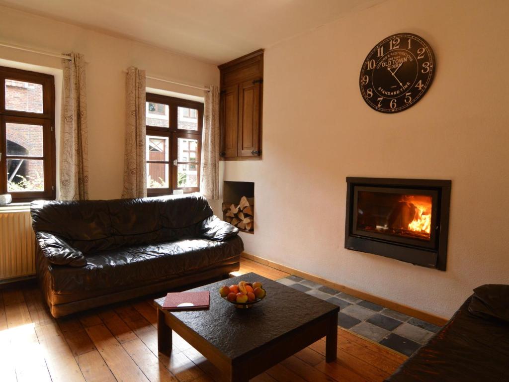 特文Spacious holiday home in Teuven with garden的客厅配有沙发和墙上的时钟