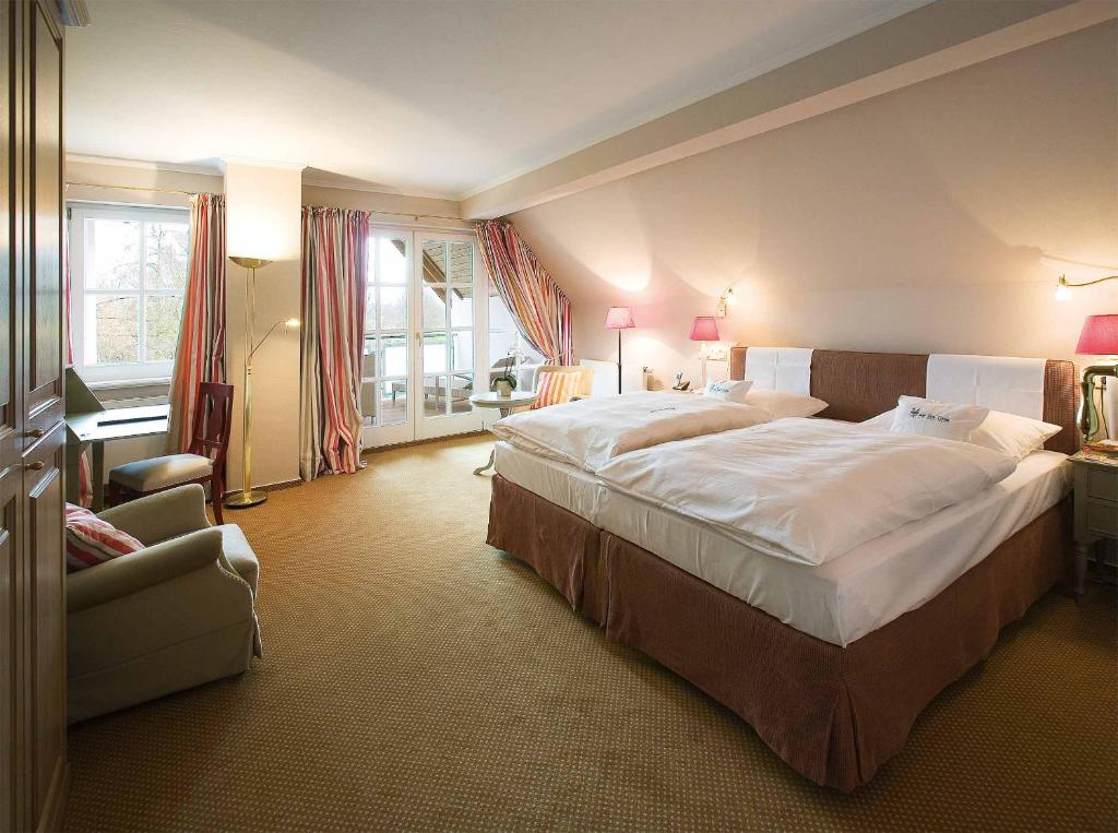 明斯特霍夫祖尔林德罗曼蒂克酒店的酒店客房带一张大床和一把椅子