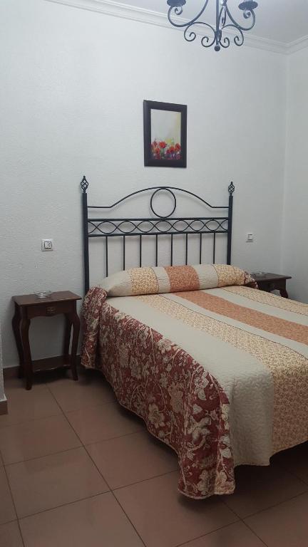 塞维利亚特拉哈诺旅馆的一间卧室配有两张床、一张桌子和一张图片