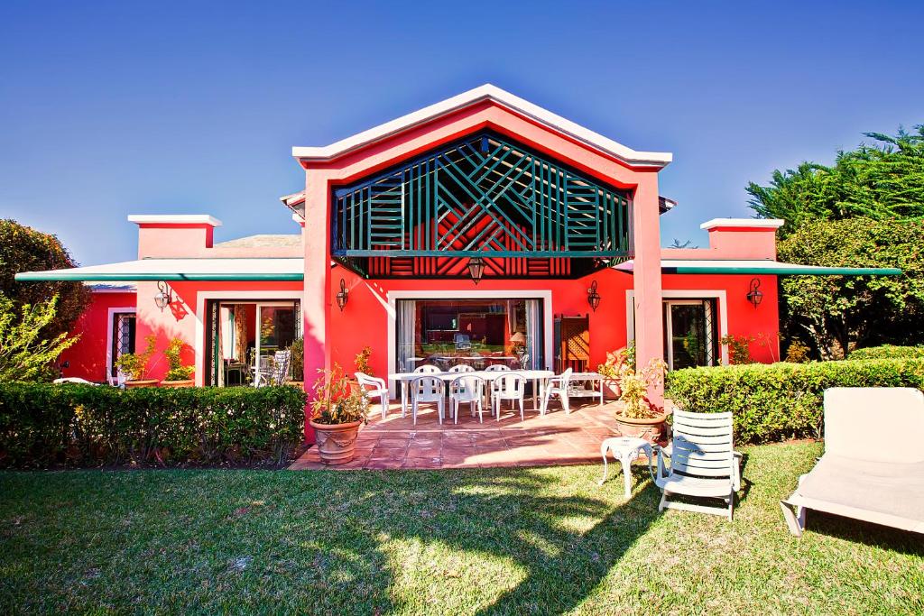 塔科龙特Luxury Villa Golf Tenerife的院子里的红色房子,配有桌椅