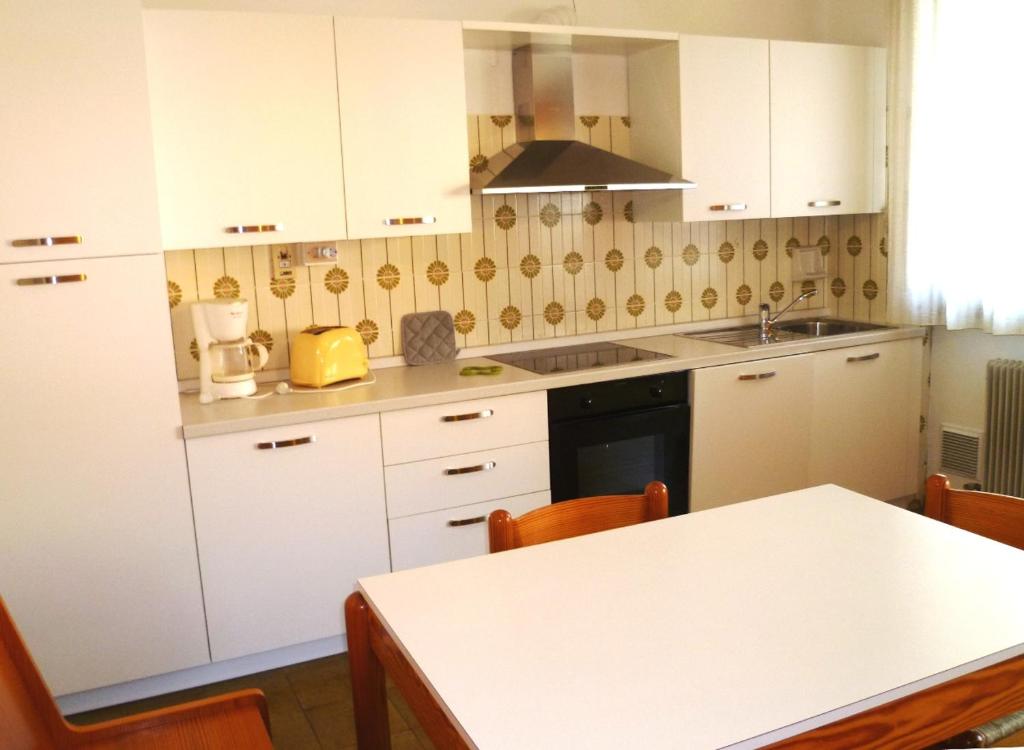 托尔博莱Casa Lucia的厨房配有白色橱柜和桌椅