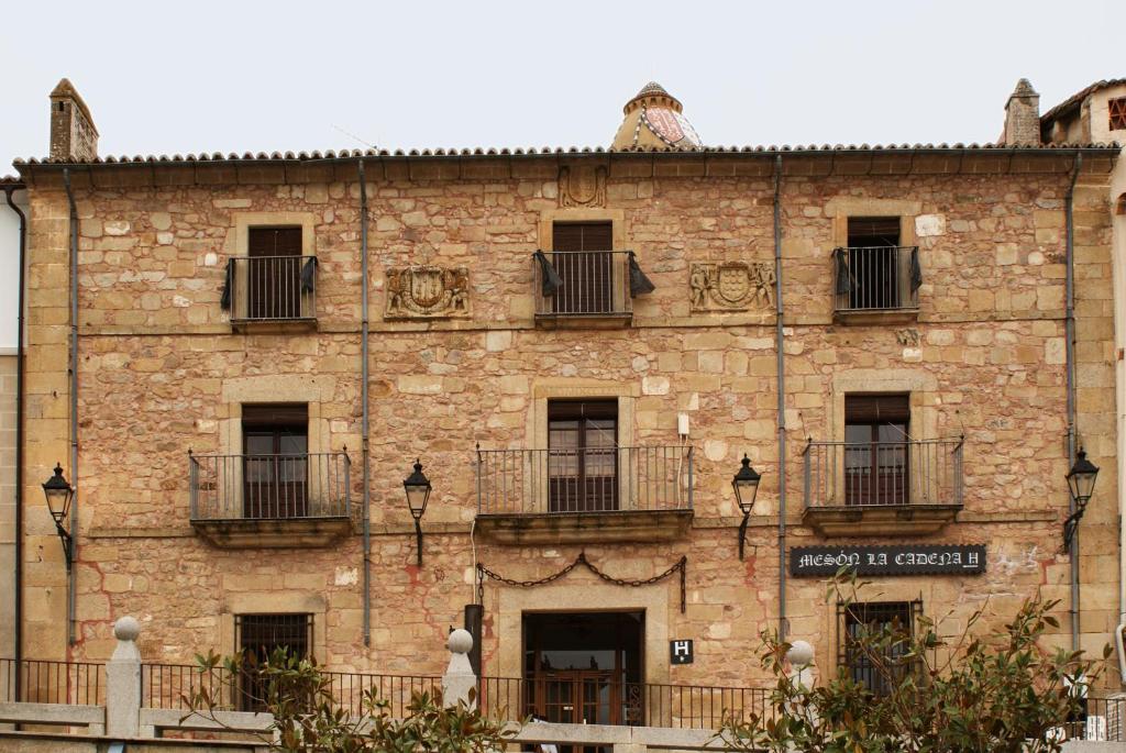 特鲁希略Hostal Meson la Cadena的大型砖砌建筑,设有窗户和阳台