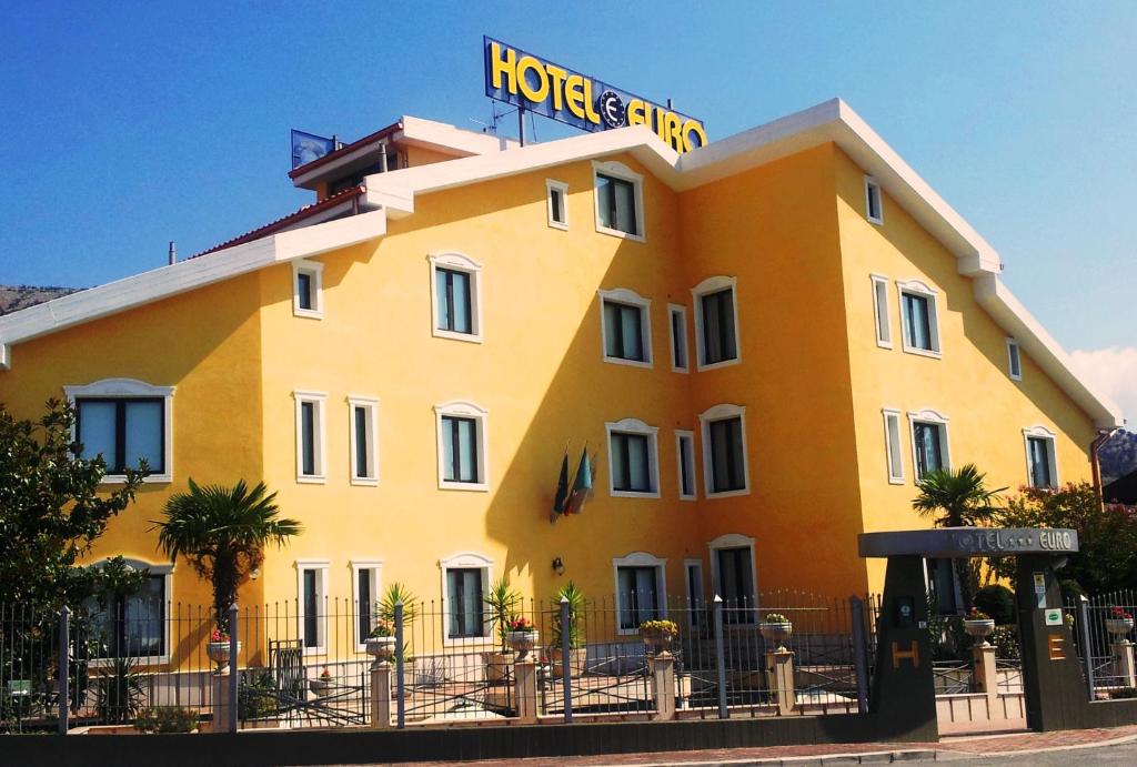圣乔瓦尼·罗通多欧元酒店的一座黄色的大建筑,上面有酒店标志