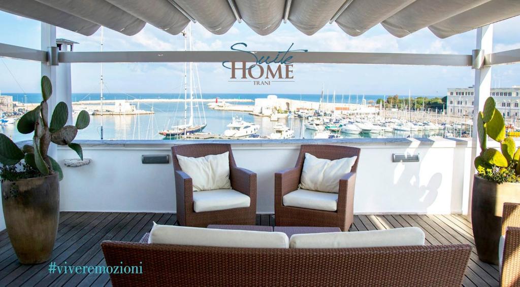 特拉尼B&B Suite Home Trani的阳台配有两把椅子,码头设有船只