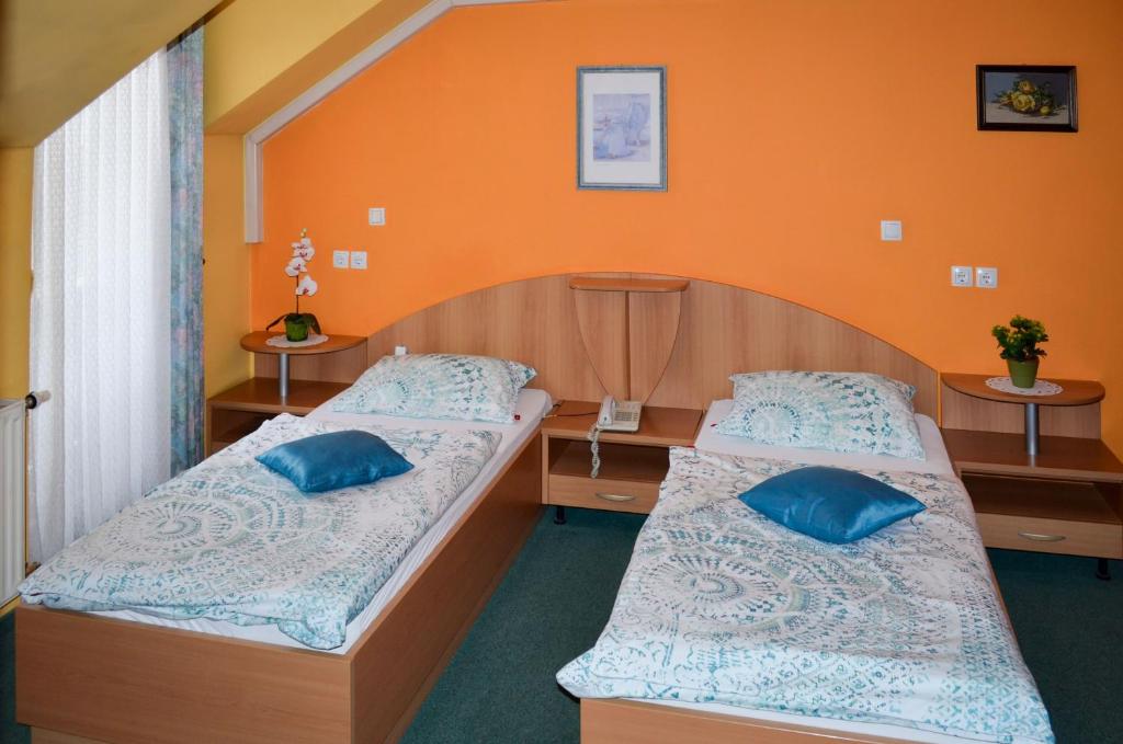 多姆扎莱Penzion Gostilna Keber的橙色墙壁客房的两张床