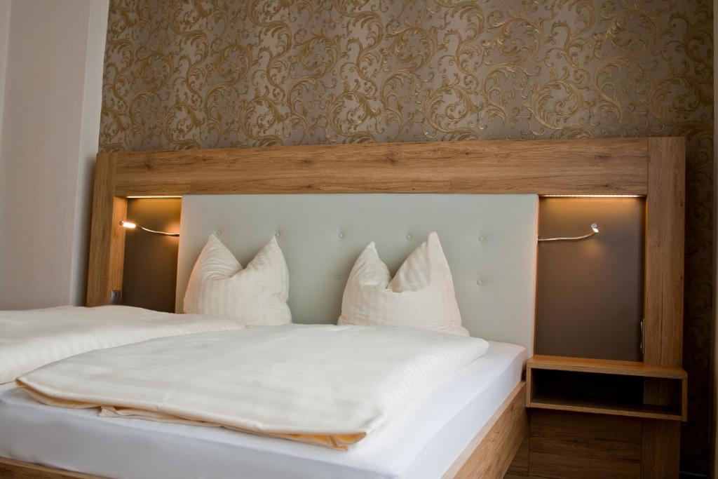 巴特萨尔茨乌夫伦Weinhotel Römerbad的一间卧室配有带白色床单和枕头的床。