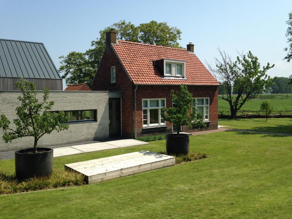 布雷斯肯斯Dijkhuis Breskens的一座红色屋顶的房子,在院子里有两棵树