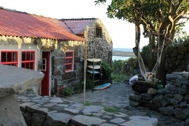 Fajã da Caldeira de Santo CristoCasa da Lagoa AL 416的一座石头房子,设有红色的门和岩石院