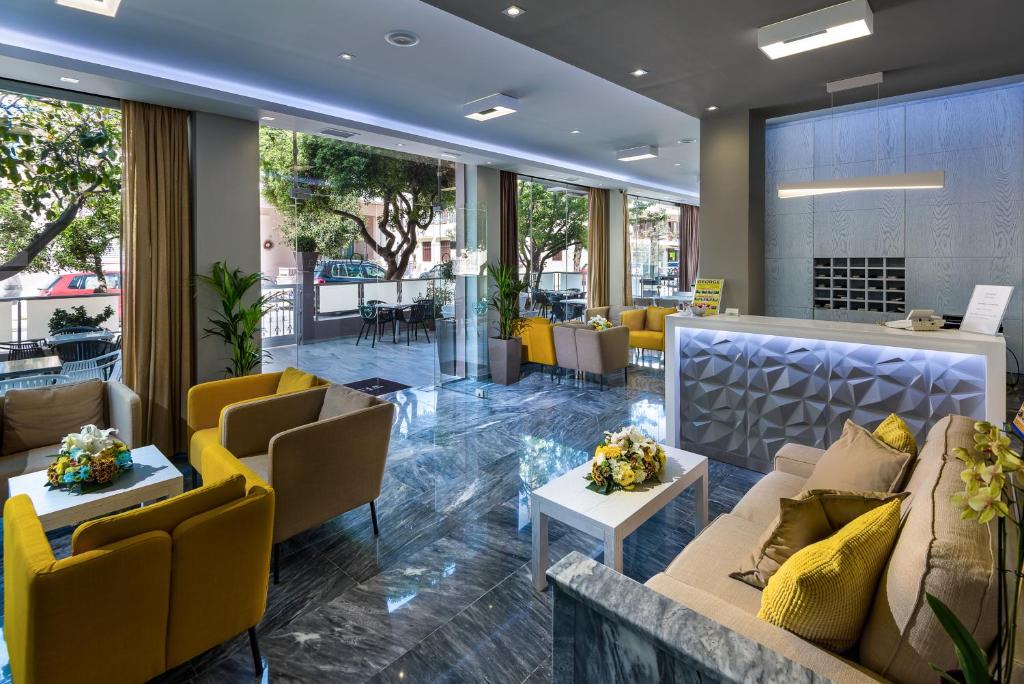 科斯镇奥林匹亚酒店的大堂配有沙发、桌子和黄色椅子