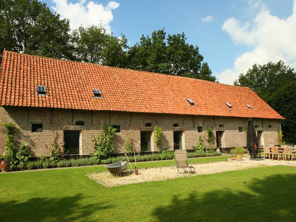 贝尔内姆Rural holiday home in former stables的一座大型砖砌建筑,屋顶橙色