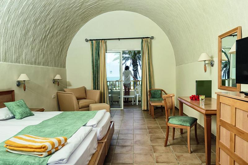 纳布勒CALIMERA Delfino Beach Resort & Spa的酒店客房配有一张床、一张书桌和一台电视。