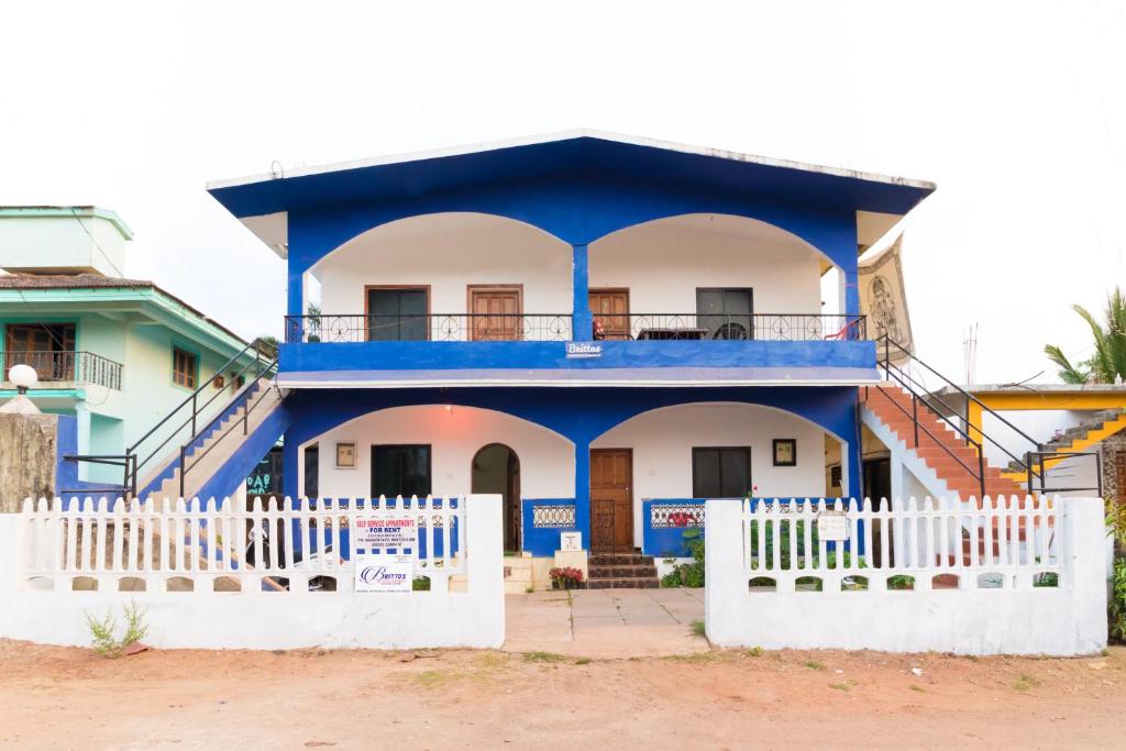 曼德姆Brittos Homestay的白色的蓝色房屋,设有白色的围栏