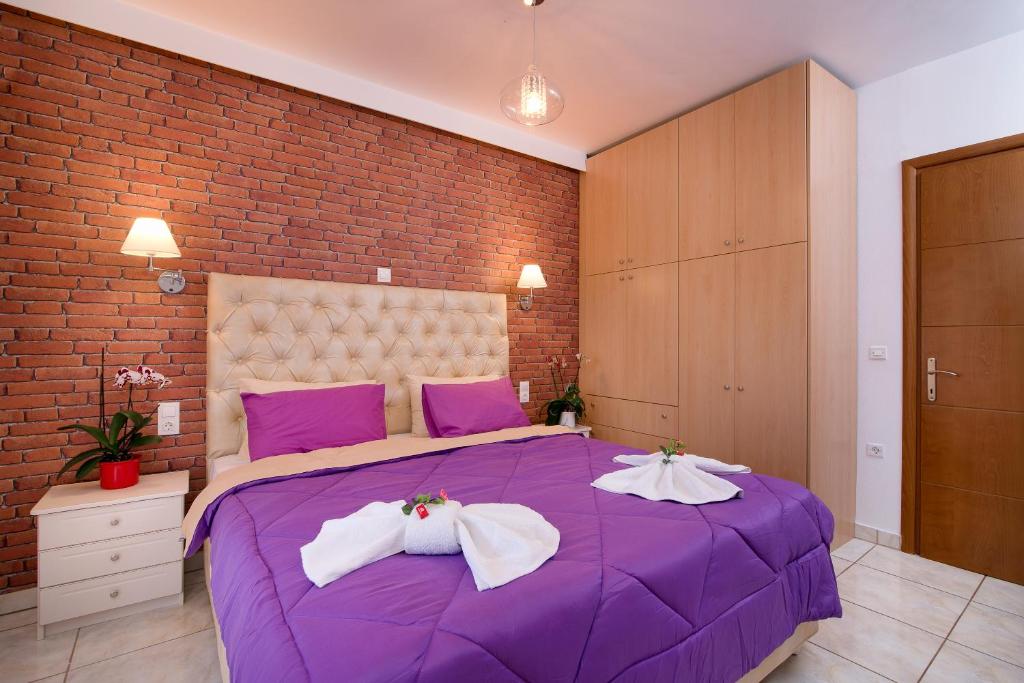 萨索斯Mouses Apartments的砖墙客房内的紫色床
