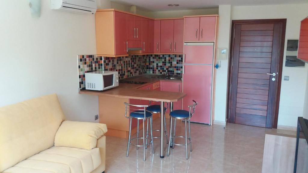 阿里纳加Viva Cruce de Arinaga的厨房配有红色橱柜和带凳子的台面