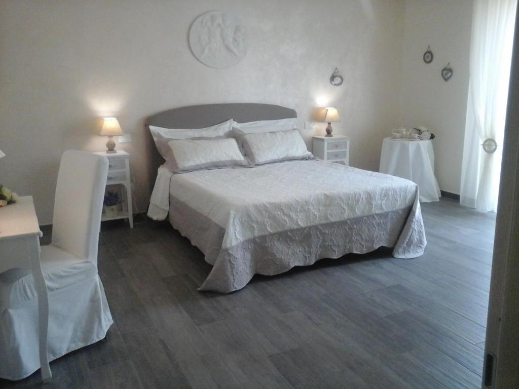 斯培西亚Carpe Diem的卧室配有一张白色的大床和两张桌子