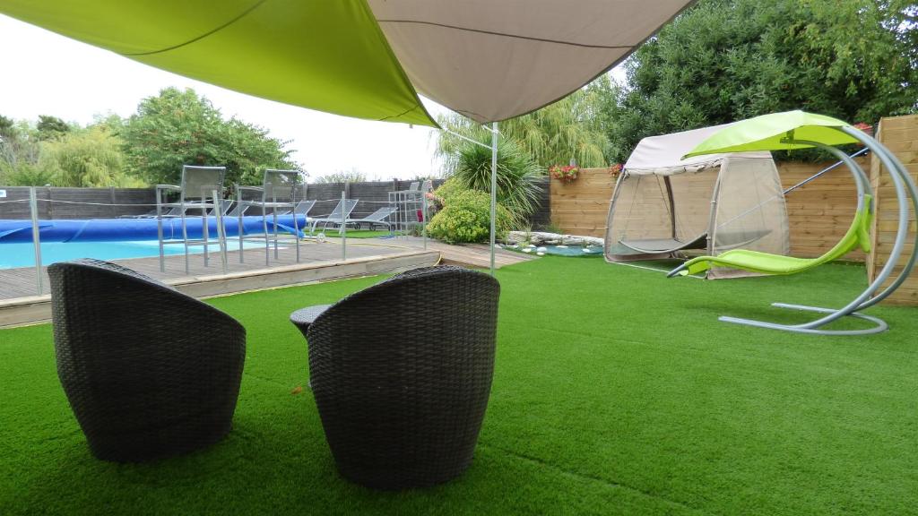 阿尔桑雷太阳伞酒店的一个带两把椅子的草坪、一个帐篷和一个游泳池