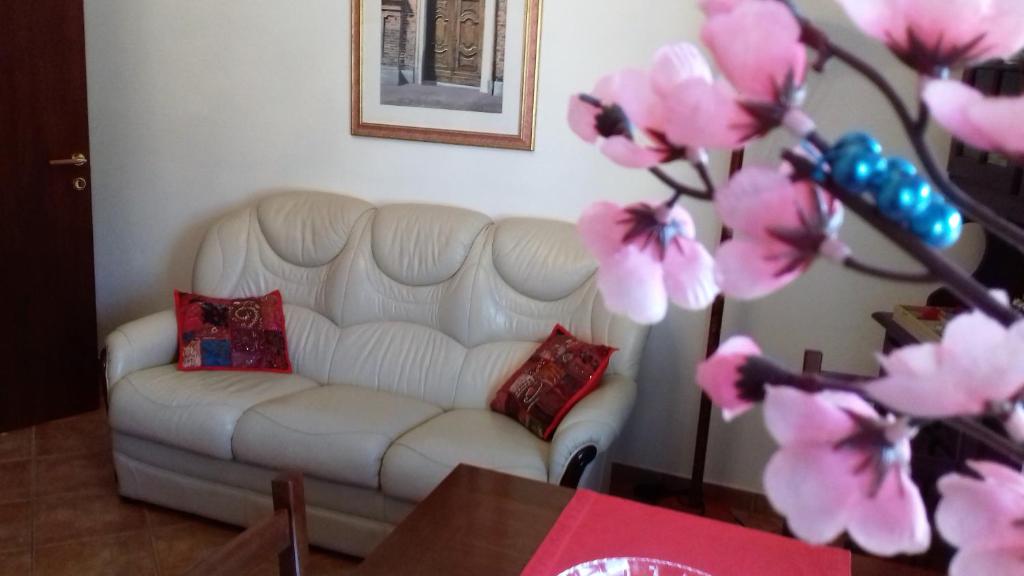 阿罗纳Appartamento Corallo的客厅配有白色沙发和粉红色的鲜花