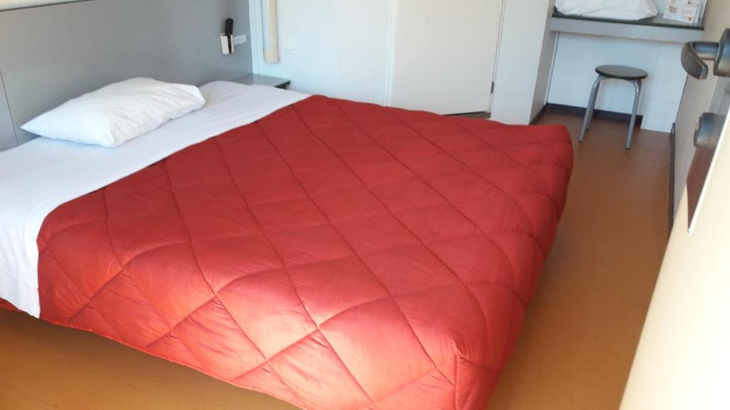 里摩日北里摩日普瑞米尔经典酒店的卧室配有红色毯子,位于床上