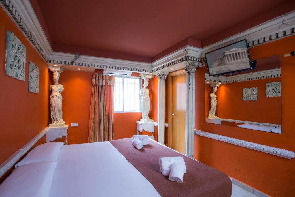 瓦伦西亚Casual Civilizaciones Valencia的一间卧室设有橙色的墙壁和一张带毛巾的床