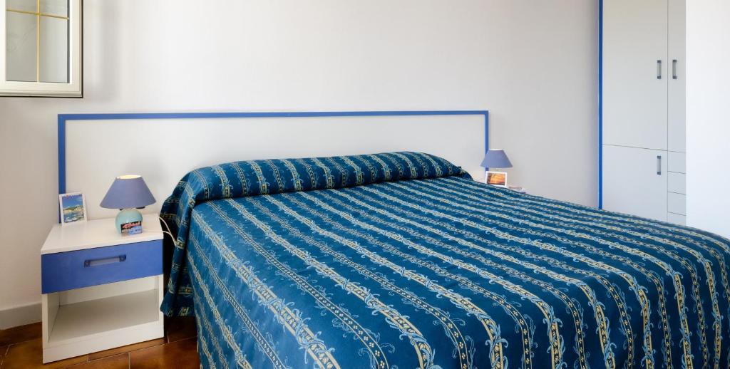 托雷瓦多Al Porticciolo的一间卧室配有一张带蓝色被子的床和两盏灯。