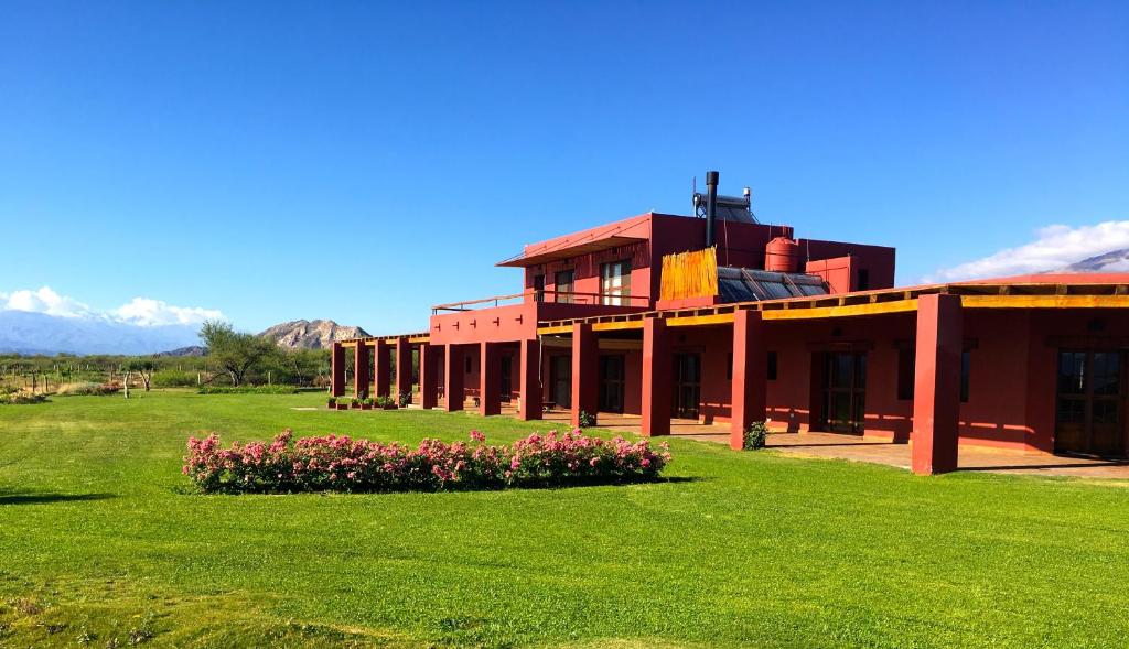 Fuerte QuemadoFinca Albarossa的一座红色的建筑,在田野里种着鲜花
