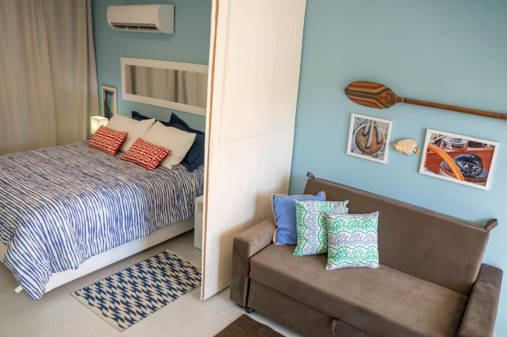 皮帕Apartamento Solar Água 107的一间卧室配有一张床、一把椅子和镜子