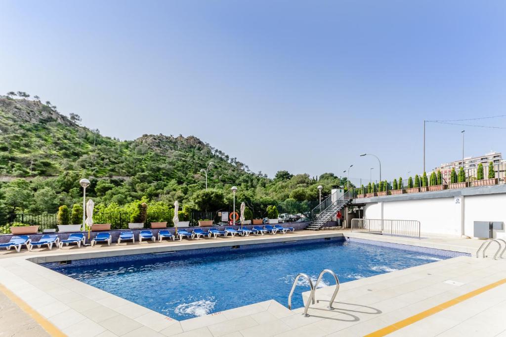 阿利坎特玛雅酒店的一个带蓝色椅子的游泳池和一个山