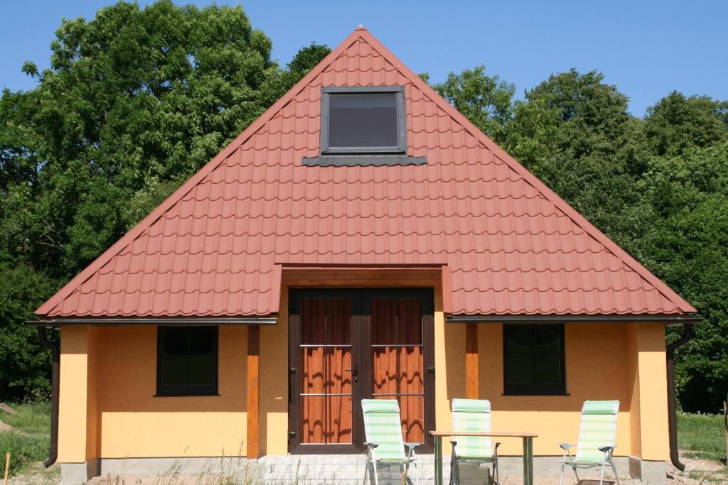 PelčiFox House的一间设有红色屋顶和椅子的小房子