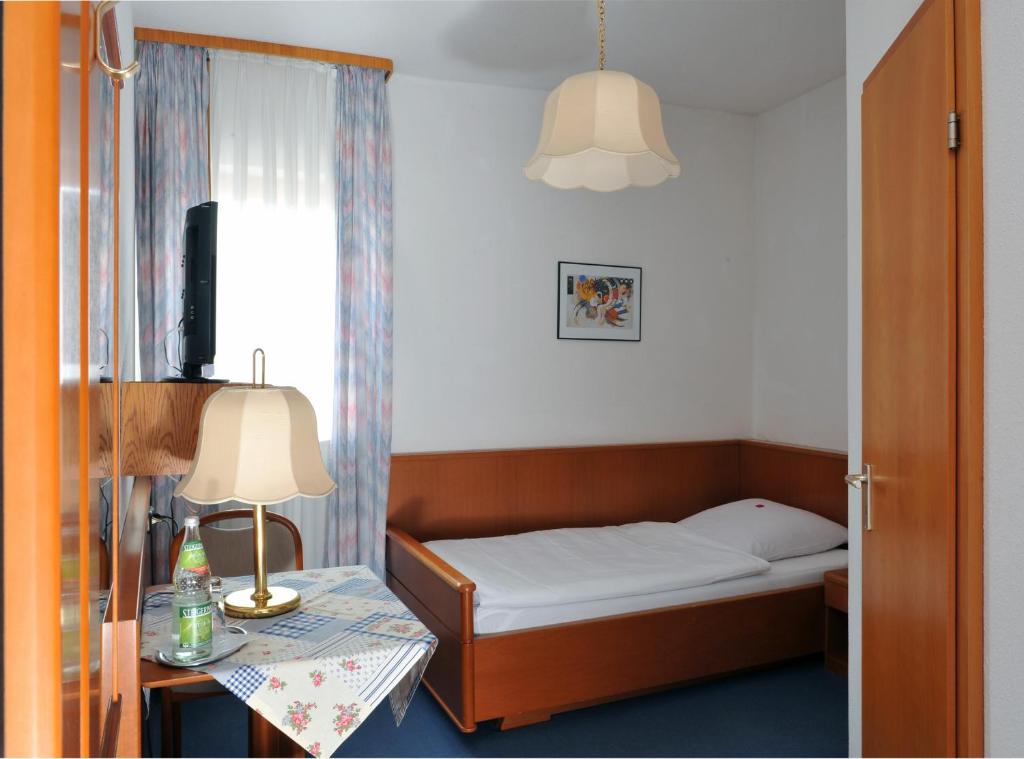 Pommersfelden格鲁纳鲍姆酒店的一间小卧室,配有一张床和一张带台灯的桌子