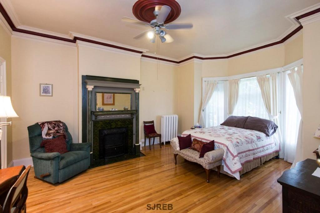 圣约翰坦纳斯之家住宿加早餐旅馆的一间卧室配有一张床、一把椅子和一个壁炉