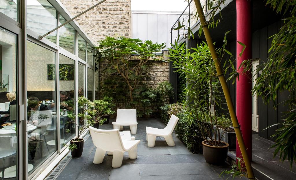 巴黎贝西广场酒店的建筑中带白色椅子和植物的庭院