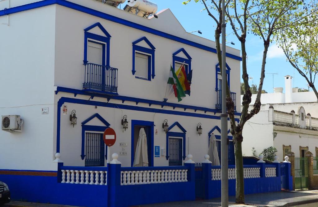 奇皮奥纳Hostal El Puerto Boutique的蓝白色的建筑,前面有树