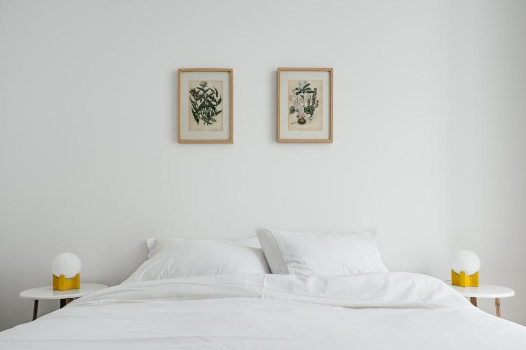 里斯本The Lisboans Apartments的一张白色的床,墙上有两张照片