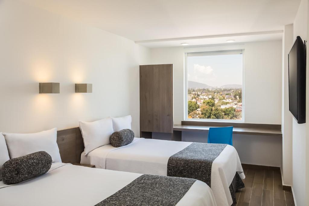 瓜达拉哈拉One Guadalajara Expo的酒店客房设有两张床和窗户。