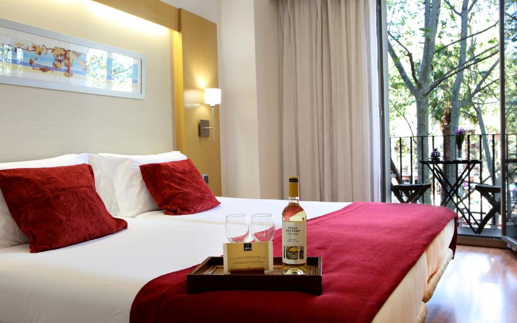 巴塞罗那阿巴兰布拉酒店的一间酒店客房,床上备有一瓶葡萄酒和眼镜