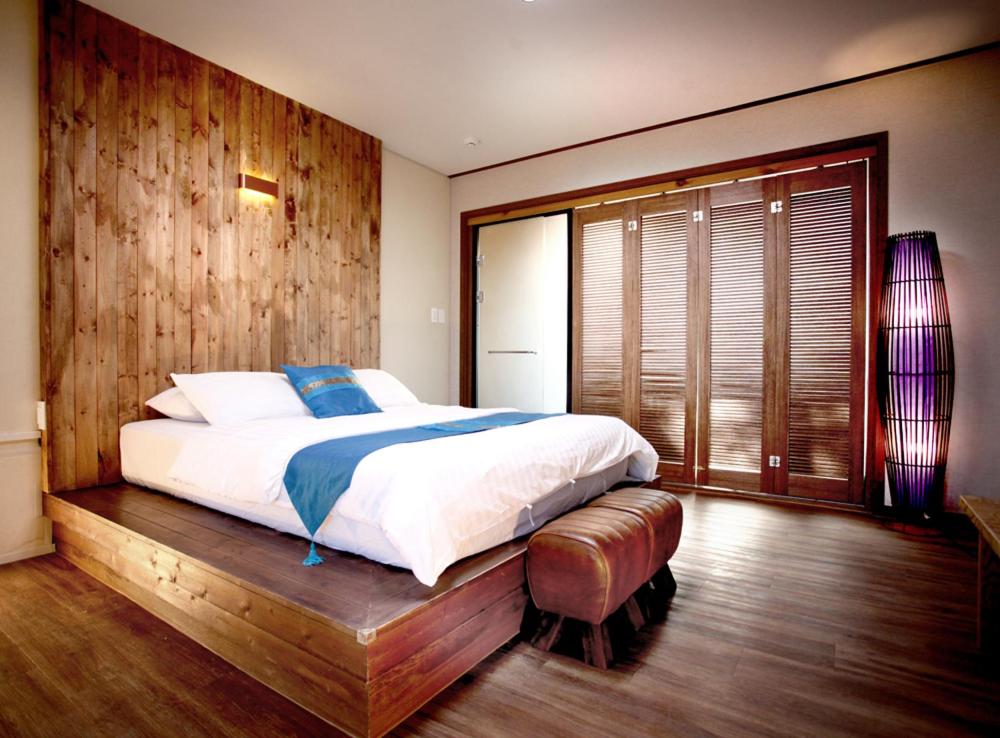 西归浦市泰国故事度假屋的一间卧室设有一张大床和木墙