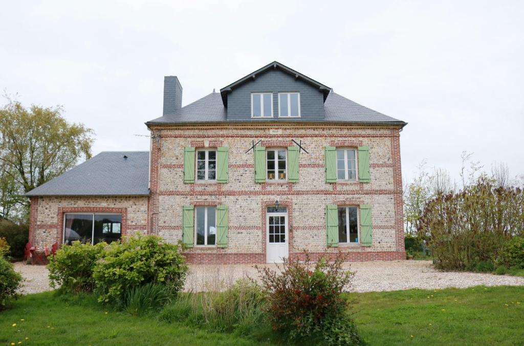 曼尼克维尔Chambres d'Hôtes " Le Clos des Colimaçons "的一座带绿色百叶窗的老砖屋
