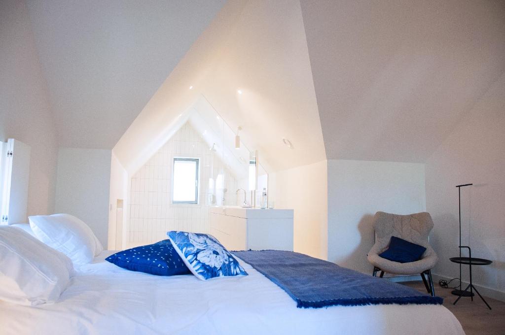 诺尔贝克Maison Village的卧室配有一张白色大床和一把椅子