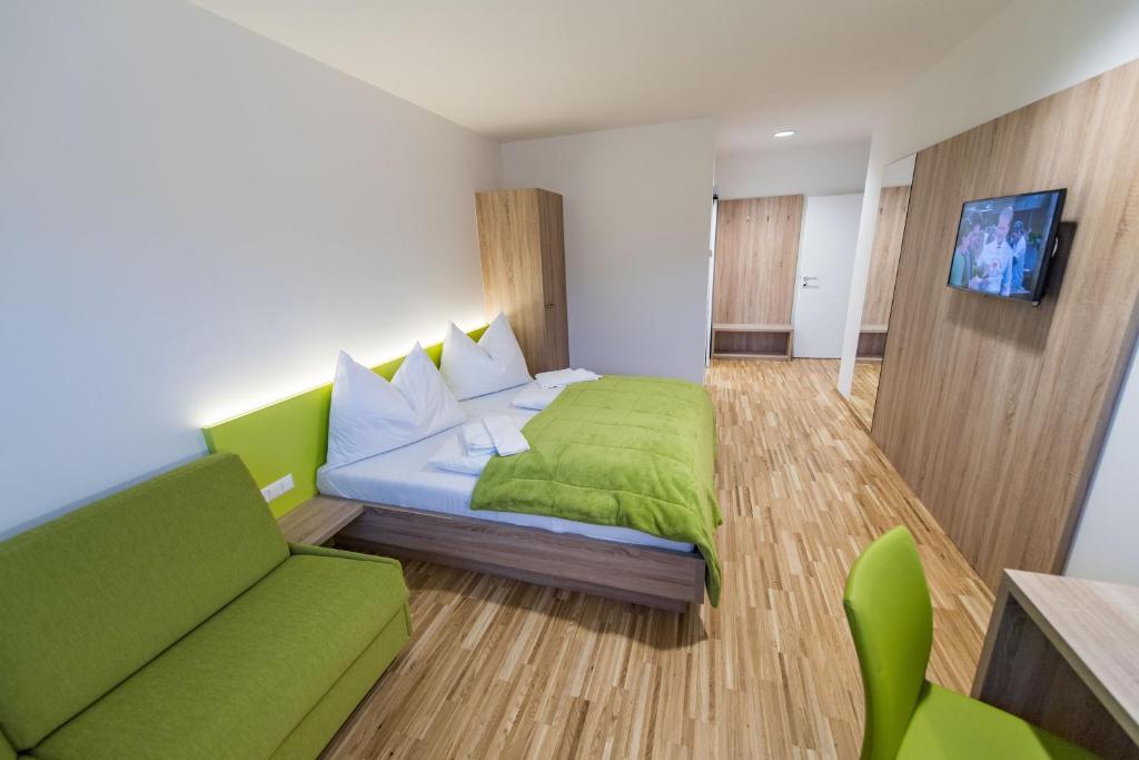 格拉茨附近卡尔斯多夫迈耶餐厅酒店的一间卧室配有绿色的床和沙发