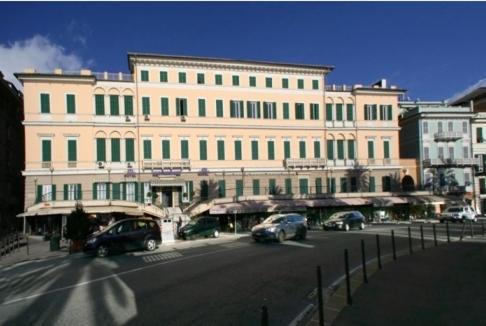 热那亚米迪特拉奈酒店的街道前有车辆停放的大建筑