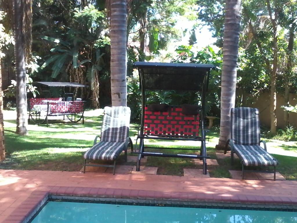 比勒陀利亚蒙大拿精品宾馆的一组三把椅子坐在游泳池旁