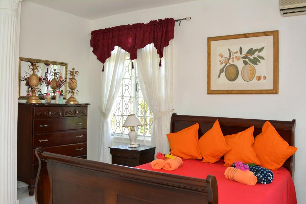 蒙特哥贝Paradise Palms Jamaica Vacation Rental的一间卧室配有带橙色枕头和梳妆台的床